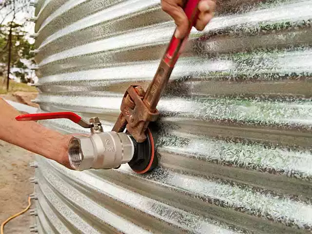 Man wrenching on a fitting to a corrugated steel tank