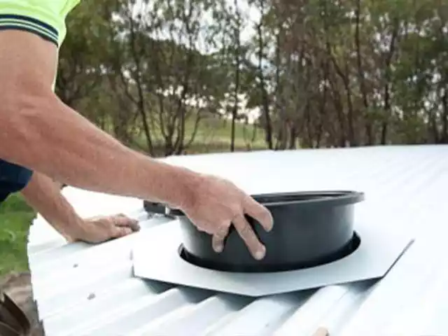 man installing an inlet on top of his corrugated steel tank