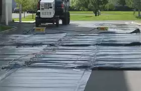 Multiple concrete curing blankets deployed over wet concrete