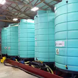 Five cone bottom tanks on stands in a warehouse