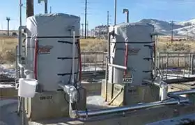 Two tanks wrapped with heater blankets on concrete pads